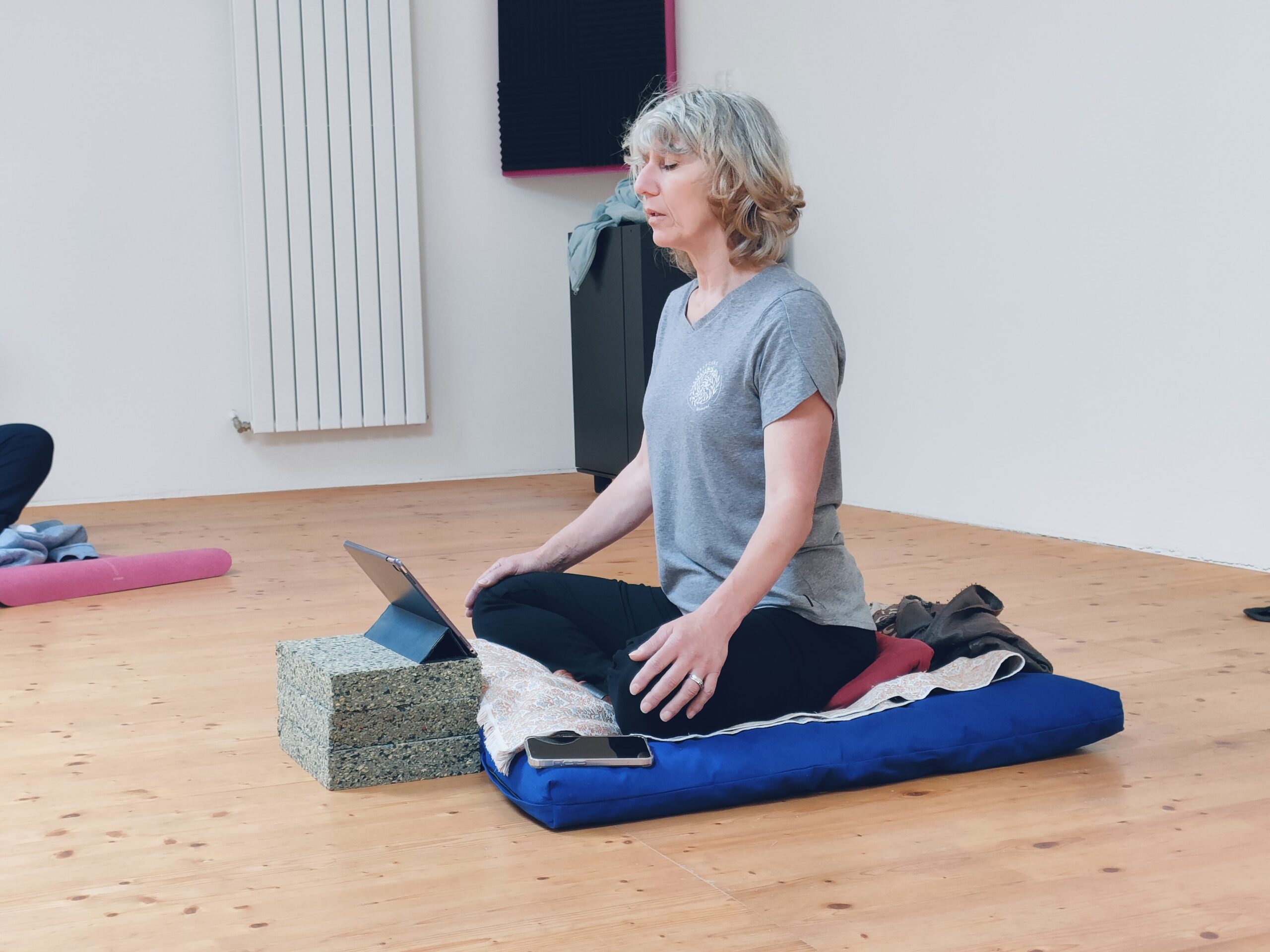 Professeure assise en tailleur sur un coussin de méditation