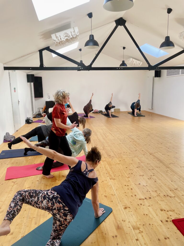 Élèves en posture de yoga guidés par la professeure